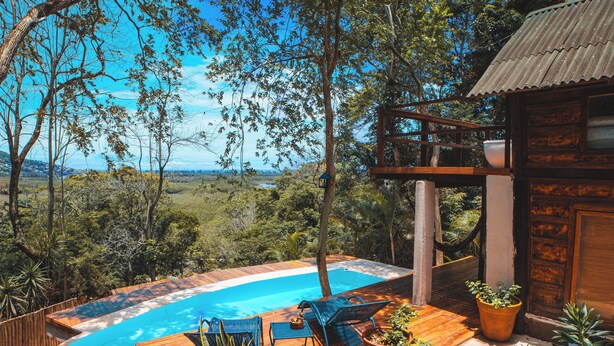 Una terraza de madera con piscina, sillas de descanso y plantas en macetas.