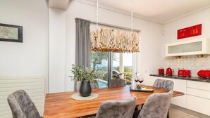 Una cocina moderna con electrodomésticos rojos, una mesa de madera con cuatro sillas y vistas al exterior.