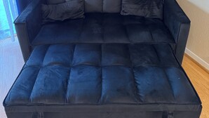 Ein dunkelblaues, gepolstertes Sofa mit rechteckiger Form und Holzboden.