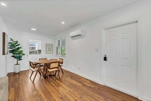 A room with a wooden dining table, chairs, a potted plant, and a white door. - Victoria Park Oasis Walk to las Olas  Beach (Fort Lauderdale)