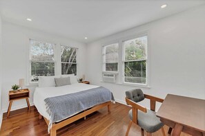 A bedroom with a wooden bed, a desk, a chair, and two windows with blinds. - Victoria Park Oasis Walk to las Olas  Beach (Fort Lauderdale)