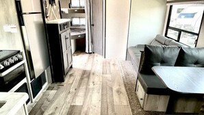 Un interno camper compatto con angolo cottura, zona pranzo e salottino.