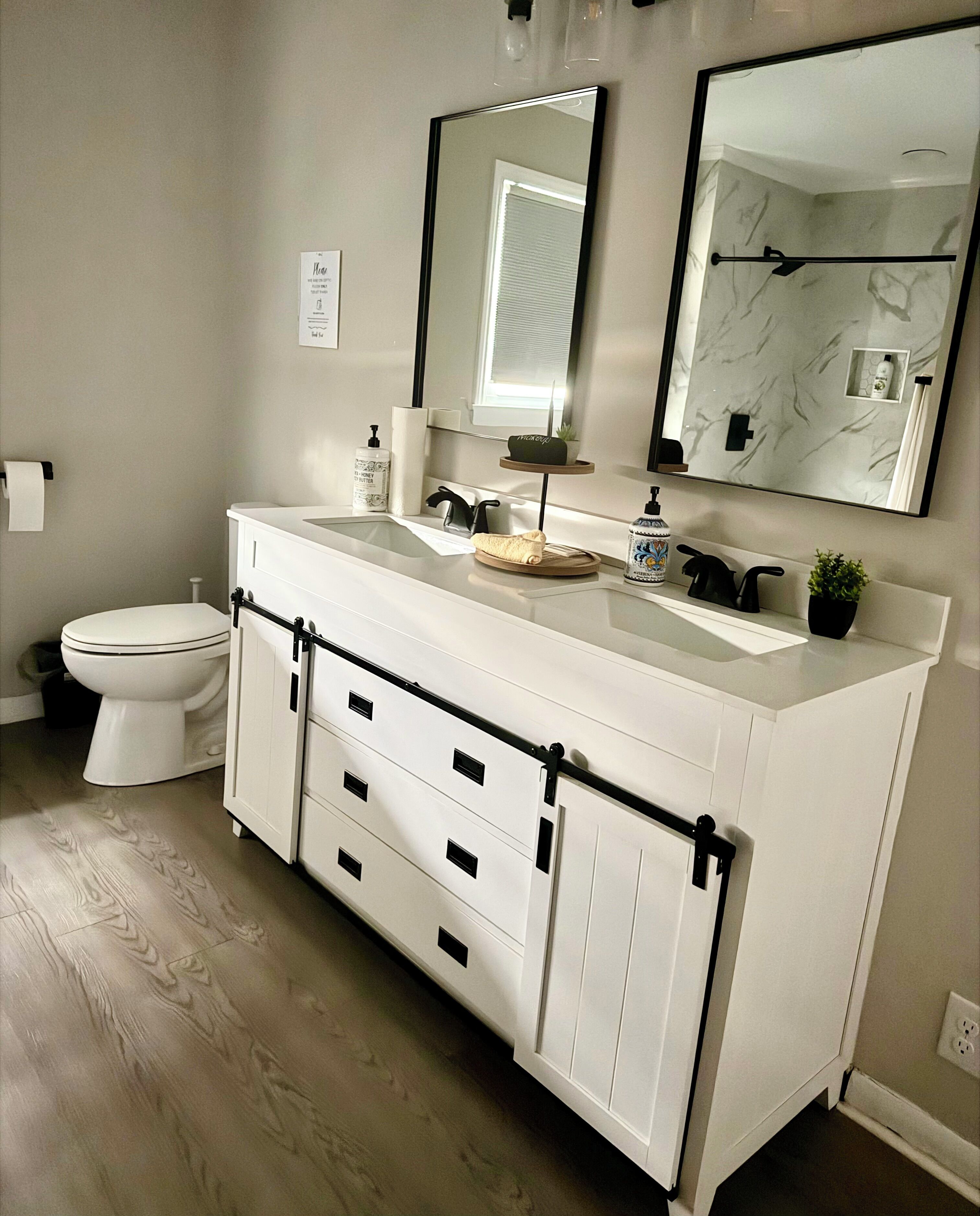 Une salle de bain moderne avec un meuble-lavabo blanc, un grand miroir et des toilettes.