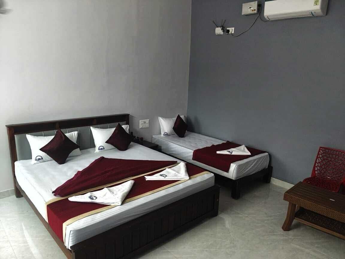 A hotel room with two single beds, a wooden headboard, a red chair, and a small table.