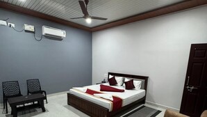 Un dormitorio con una cama, dos sillas, un sofá, una mesa de madera y un ventilador de techo.