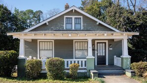 Une maison à deux étages avec un porche à l’avant, un garage et une cheminée.