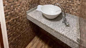 Un baño con pared de mosaicos, encimera de granito y lavamanos blanco.