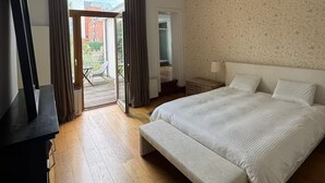 A bedroom with a large bed, a bench, a television, a ceiling light, and a view of the outside. - A paradise in the heart of Brussels (Bruxelle)