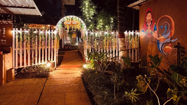 Un sendero conduce a un edificio con un arco decorativo y un mural a la derecha.