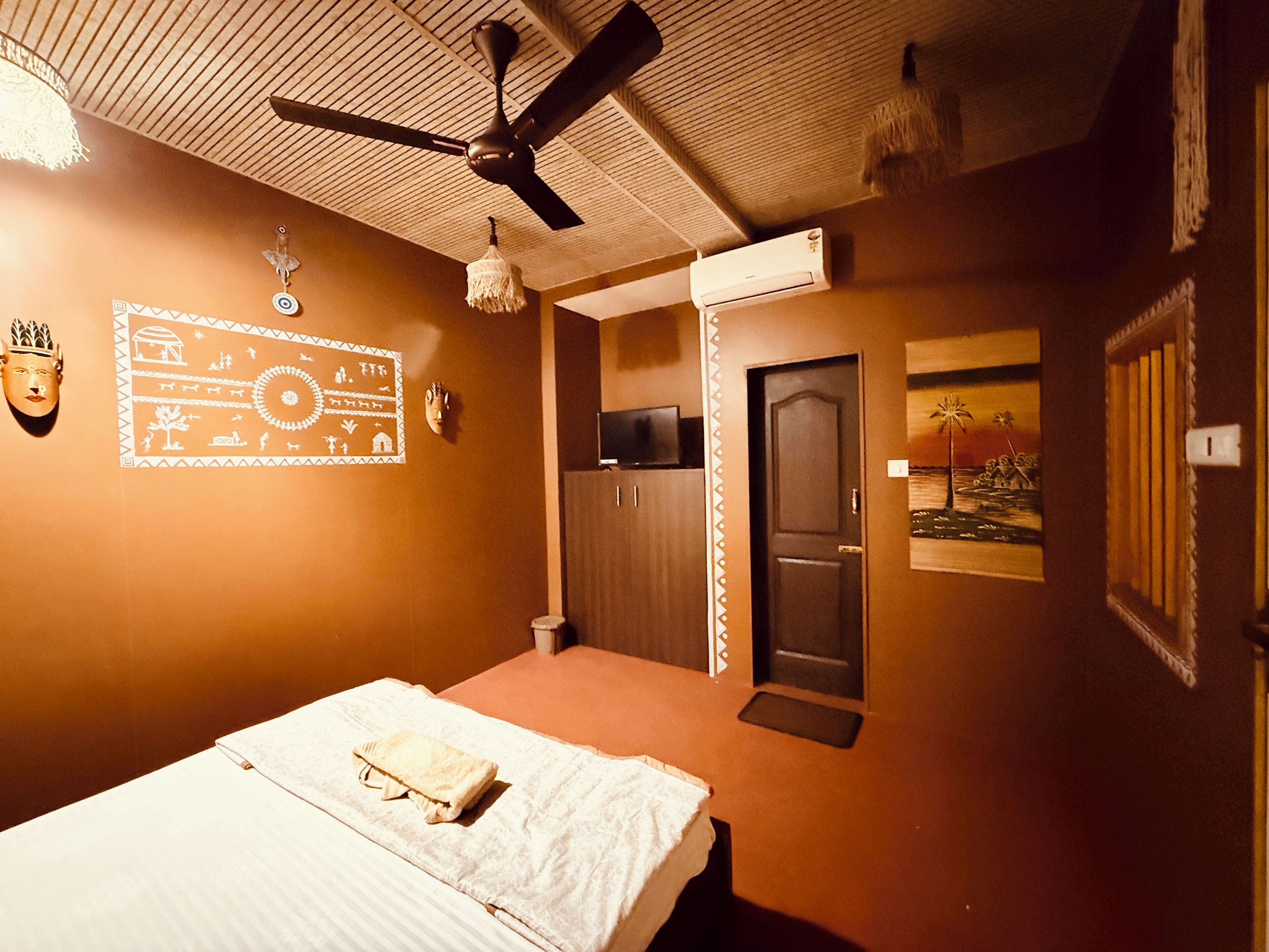 Un dormitorio con cama, ventilador de techo, aire acondicionado y una puerta con felpudo.