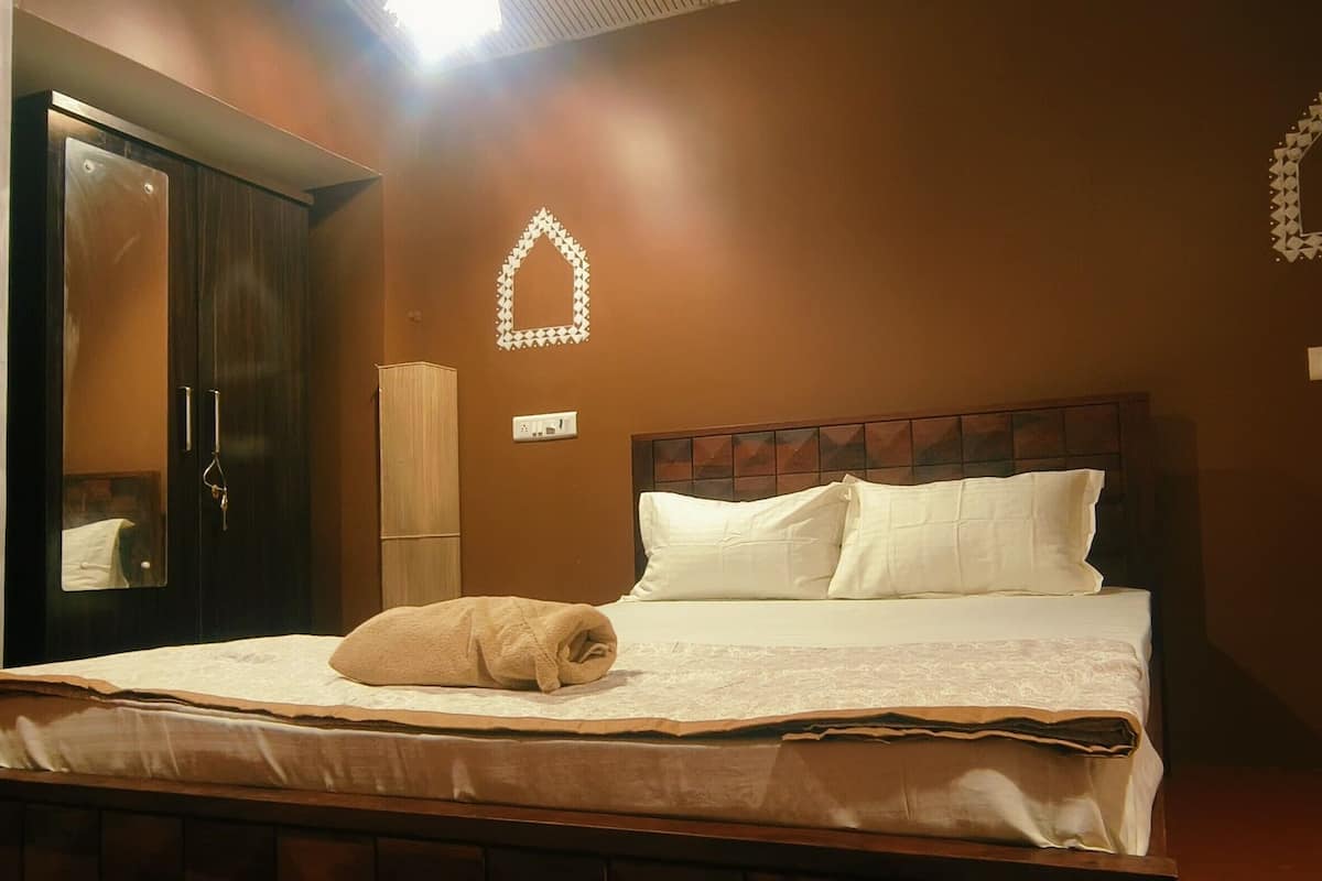 Una cama bien hecha con una colcha blanca y almohadas, un cabecero de madera y una toalla sobre la cama.