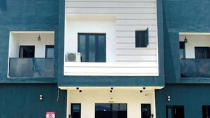 A modern building with a central white section and dark blue exterior. There are multiple windows and balconies visible. - The Majj Hotel  (Benin City)