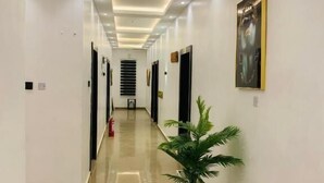 A modern hotel hallway with a marble floor, recessed lighting, and a potted plant. - The Majj Hotel  (Benin City)