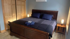 A bedroom with a large bed, wooden wardrobe, and an air conditioning unit. - Beautiful 6-bedroom house in Rangeley perfect for friends and family getaways. (Rangeley)