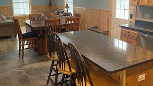 A kitchen with a large island, wooden cabinets, and a dining area with chairs. - Beautiful 6-bedroom house in Rangeley perfect for friends and family getaways. (Rangeley)