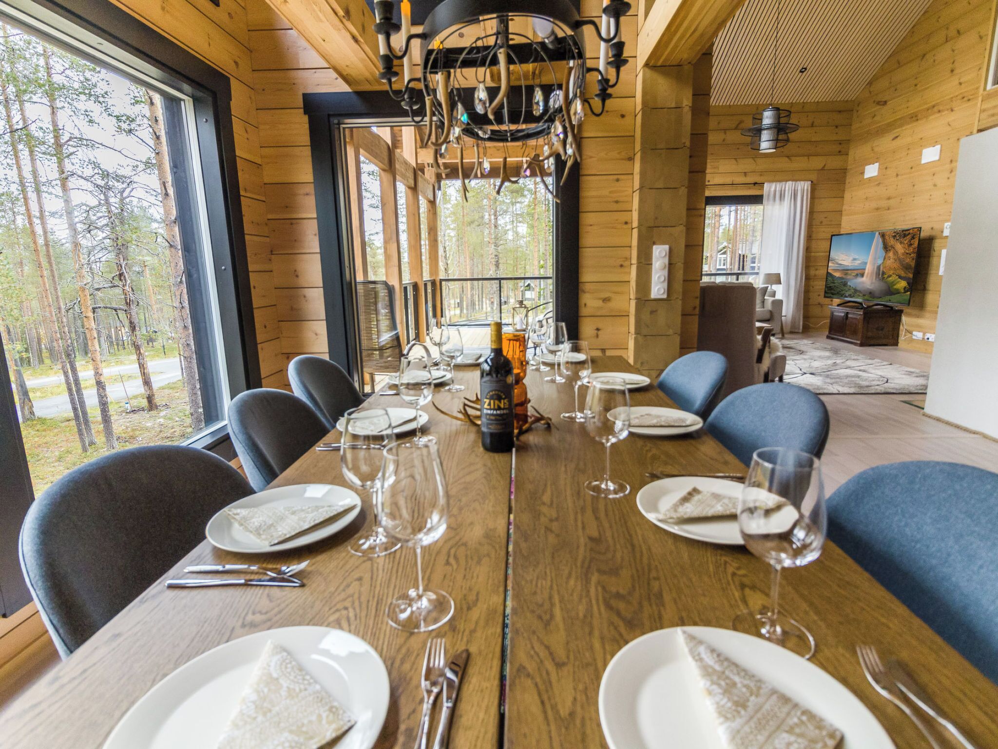 A dining area with a long wooden table set for a meal, surrounded by chairs.