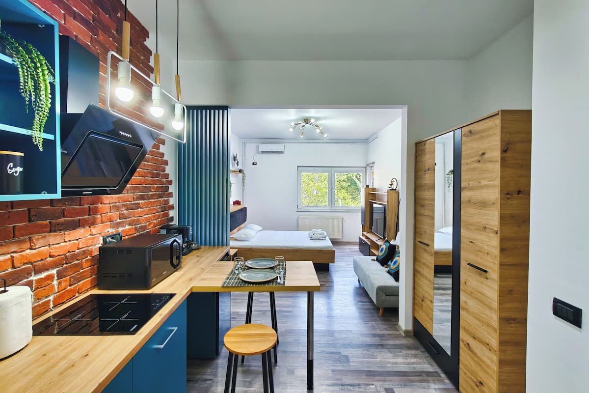 A modern kitchen with a brick wall, wooden countertop, and a built-in microwave.