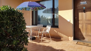 A patio with a table and chairs, a potted plant, and a door with a welcome sign. - Villa Muse Holiday oasis by the sea of CapoMulini-Acireale Holiday Rental (Capo Mulini)