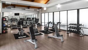 Ein Fitnessstudio mit Cardiogeräten, Krafttrainingsgeräten und Kurzhanteln.