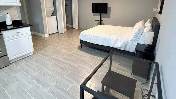 Ein gemütliches Schlafzimmer mit Bett, Schreibtisch, Fernseher und Deckenventilator.