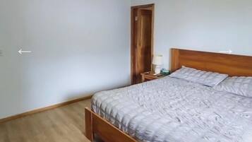 A bedroom with a wooden bed, a nightstand, and a door.