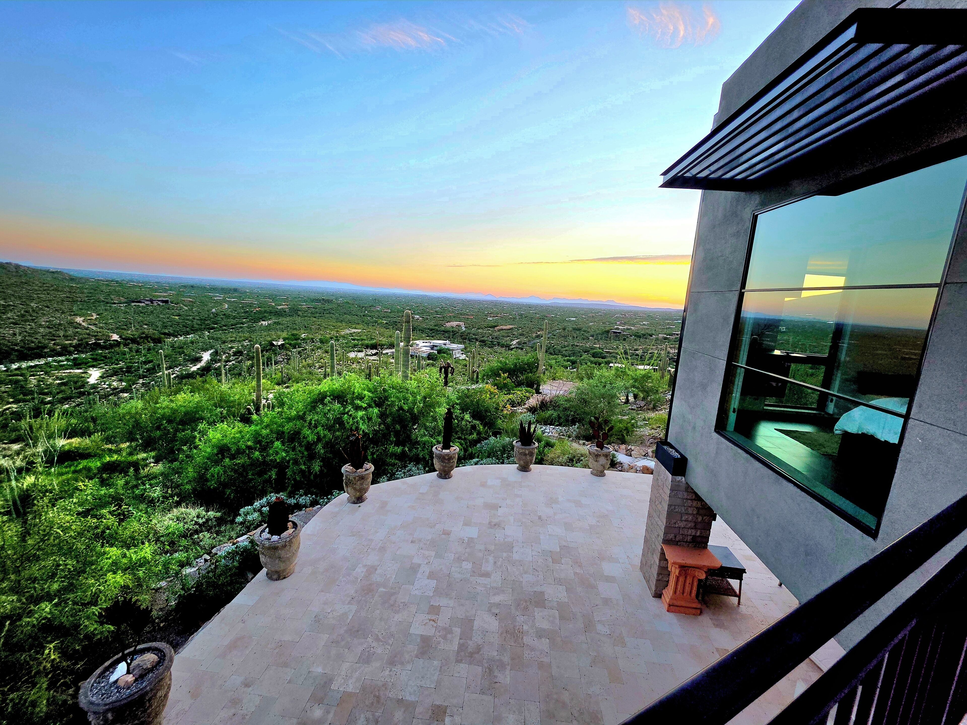 A terrace with a view of a desert landscape and a modern building with large windows.