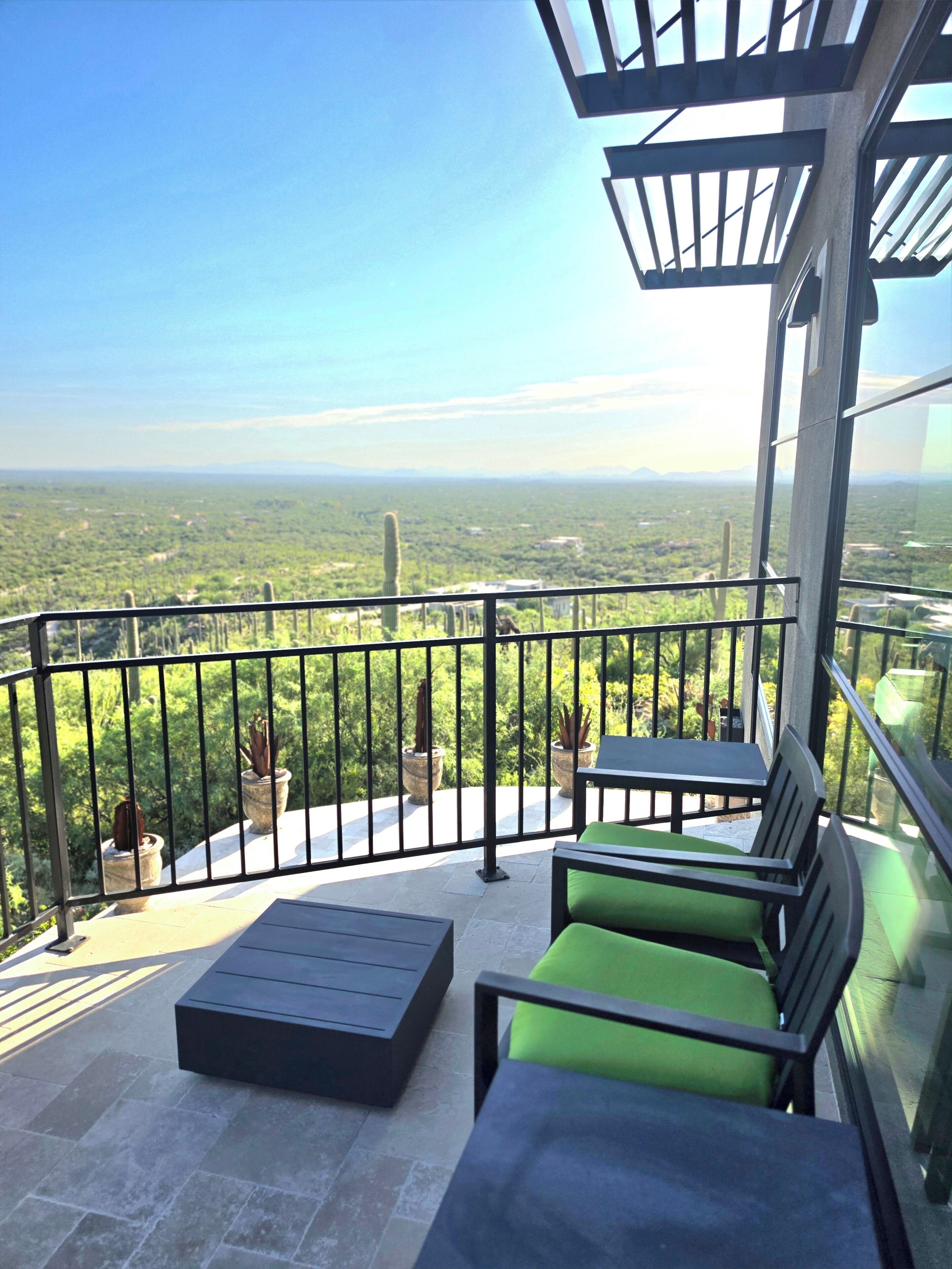 Ein Balkon mit Blick auf eine grüne Landschaft, einem Tisch und zwei Stühlen.