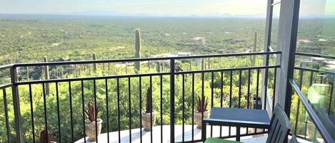 Ein Balkon mit Blick auf eine grüne Landschaft, einem Tisch und zwei Stühlen.