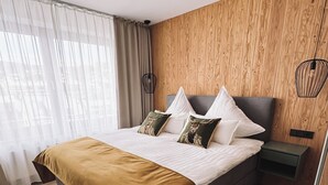 Une chambre moderne avec un mur recouvert de panneaux en bois, un lit avec une couverture marron, des oreillers blancs et un tapis vert à poils longs.