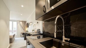Een moderne keuken met een strakke roestvrijstalen spoelbak, een marmeren achterwand en een inbouwoven.