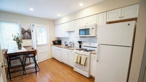 Une cuisine avec des meubles blancs, une cuisinière, un four à micro-ondes et un réfrigérateur.