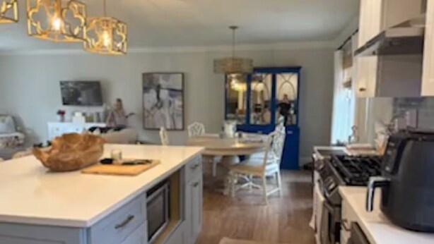 Une cuisine moderne dotée d’un grand îlot central, d’un coin repas et offrant une vue sur le salon.