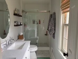 A bathroom with a white sink, mirror, and toilet. There is a shower area with a glass door. - Quail Hollow PGA Truist: Family home near club (Charlotte)