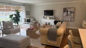 Un salon moderne avec un canapé beige, un fauteuil blanc et une table basse.