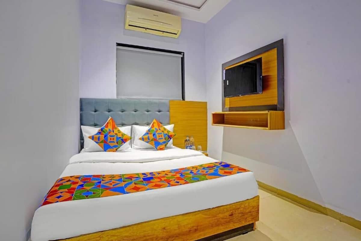 A bedroom with a bed, a TV, and a window.