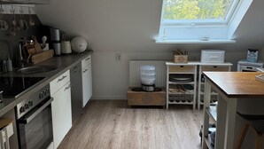 Una cocina moderna con tragaluz, piso de madera y armarios blancos.