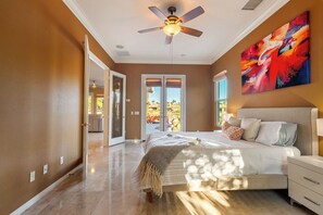 A bedroom with a bed, a ceiling fan, and a large window.