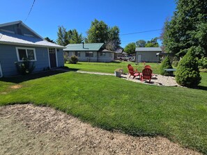 A residential area with a well-maintained lawn, a patio with chairs, and houses in the background.