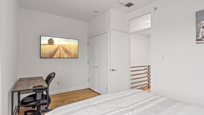 A bedroom with a bed, a desk, and a chair. There is a wardrobe and a door leading to another room. - Fancy 4BR W/ Hot Tub (Philadelphia)