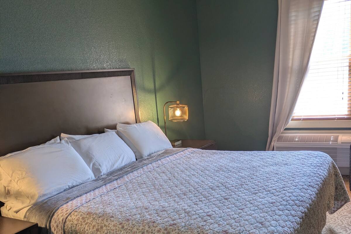 Una camera da letto con un letto, comodini, una lampada e una finestra con tende.