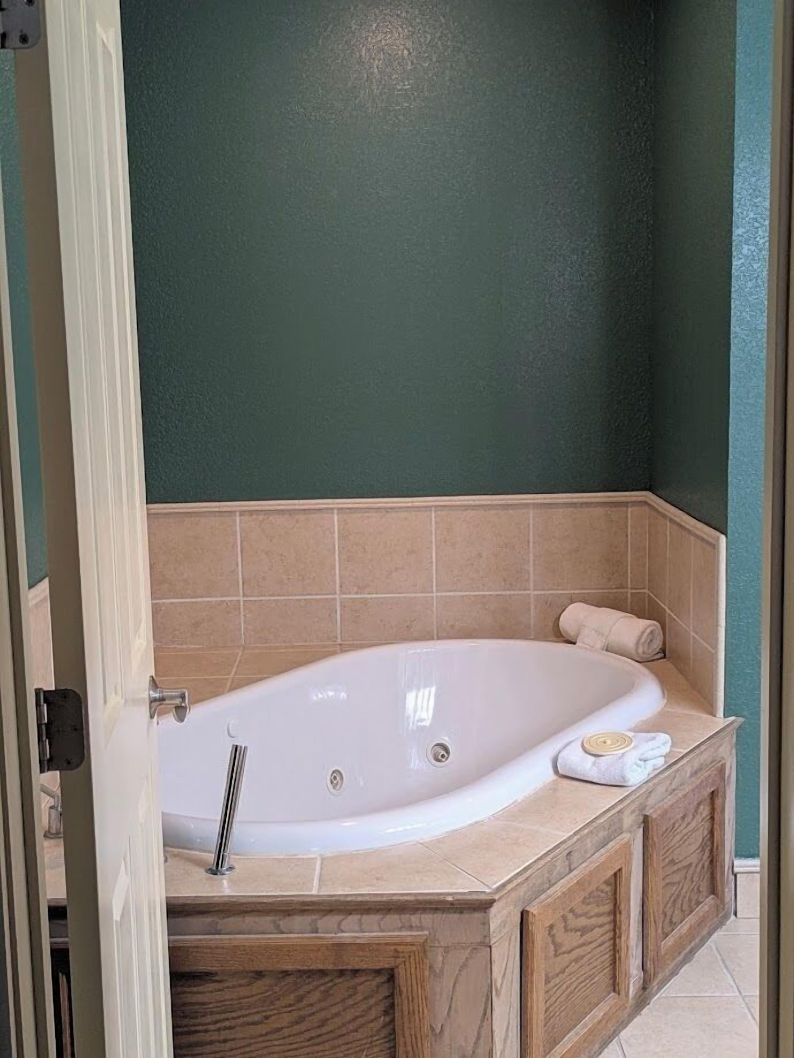 Un baño con una bañera independiente, baldosas color crema y un armario de madera.