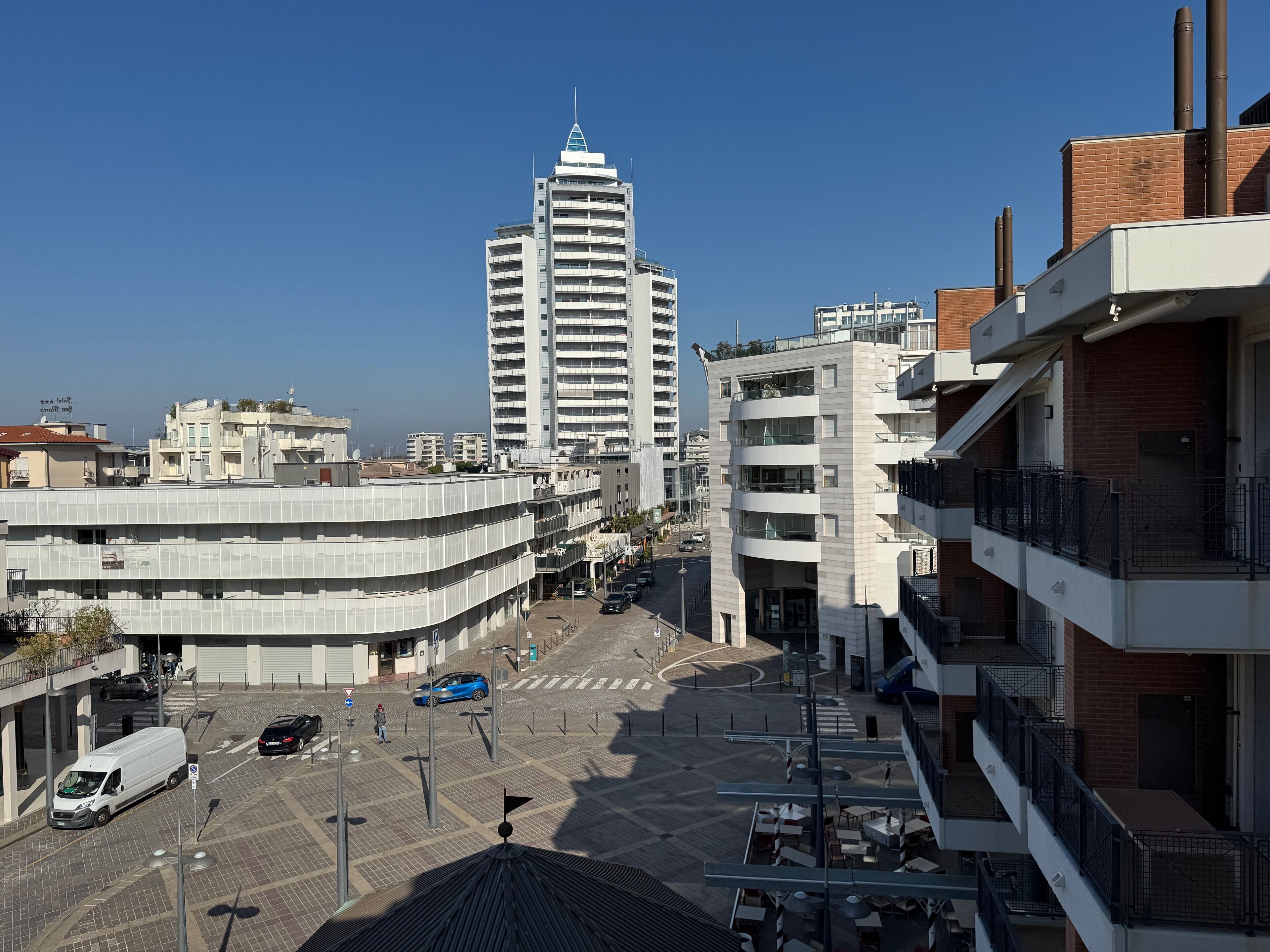 A multi-story building with a modern architectural design, featuring balconies and a rooftop terrace.