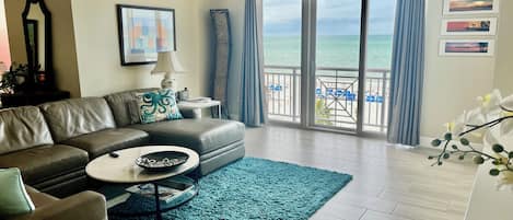 A living room with a sofa, coffee table, and a view of the ocean through large sliding doors.