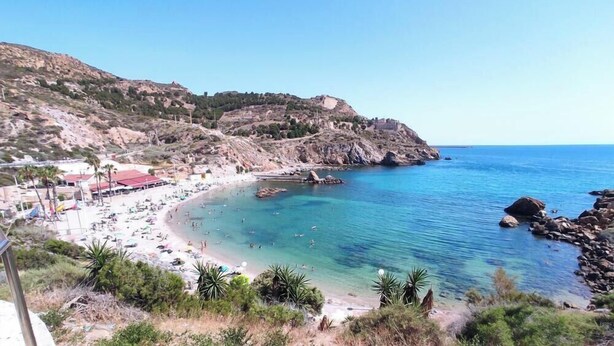 A coastal beach with clear blue waters, a sandy shore, and rocky outcrops. - Casa Ellen in Los Alcazares Spanien (Los Alcázares)