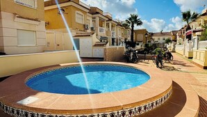 A swimming pool with a fountain, surrounded by buildings with balconies and a clear sky. - Casa Ellen in Los Alcazares Spanien (Los Alcázares)