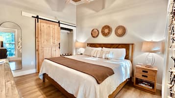 Un dormitorio con una cama, mesitas de noche, ventilador de techo y una puerta corrediza.