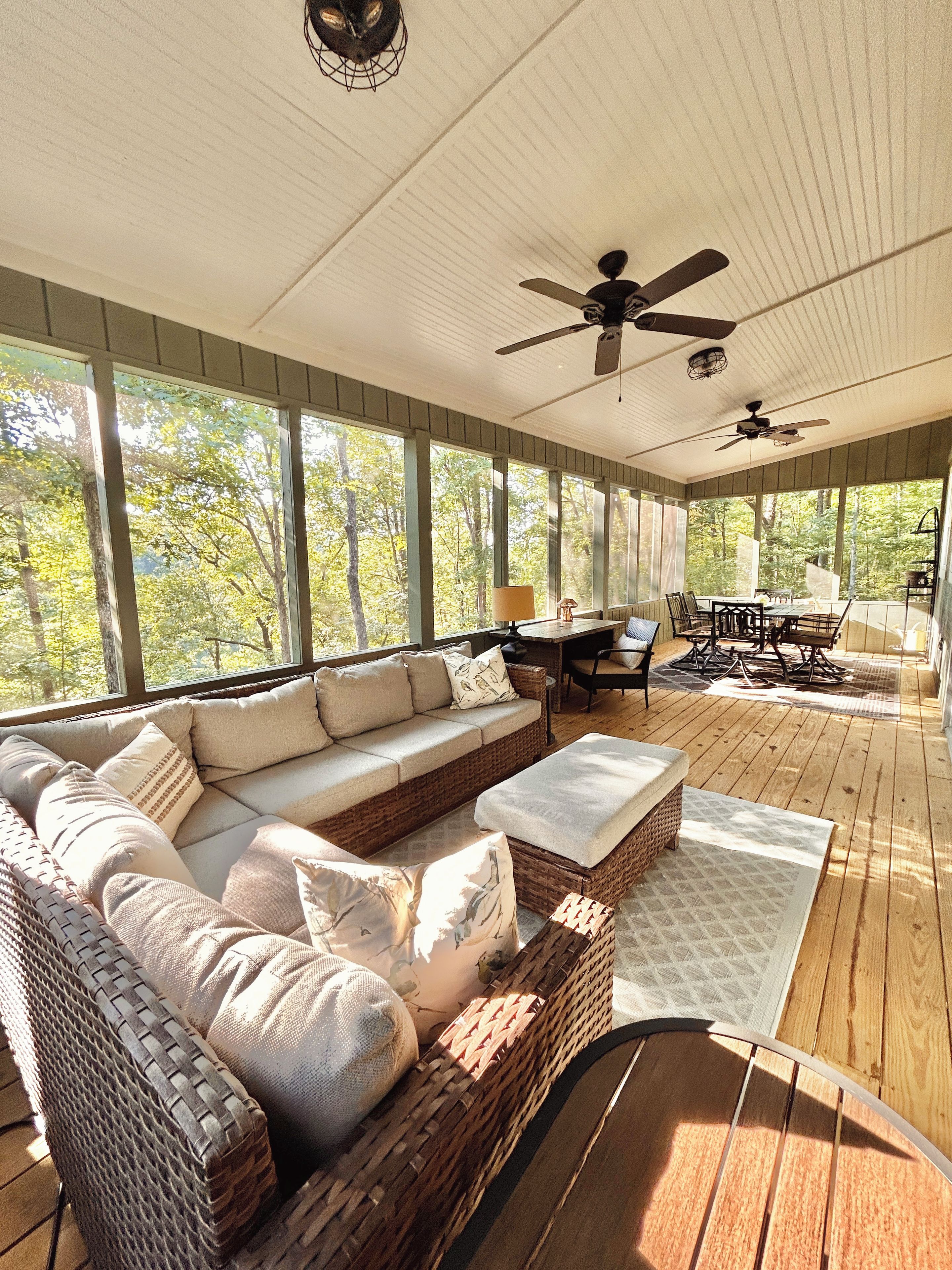 A covered outdoor seating area with a sofa, chairs, and a dining table.