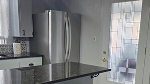 Eine moderne Küche mit schwarzem Arbeitsplatz, einem Edelstahlkühlschrank und zwei schwarzen Barhocker.