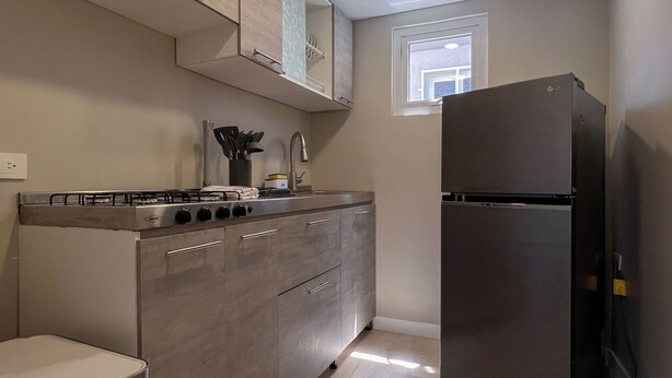Una cocina moderna con estufa a gas integrada, electrodomésticos de acero inoxidable y muebles de madera clara.