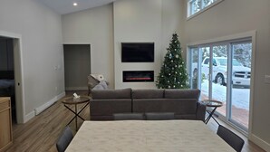 Una sala de estar moderna con un sofá grande, una mesa de comedor, un árbol de Navidad y una chimenea.